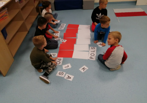 chłopcy układają kartoniki z literkami
